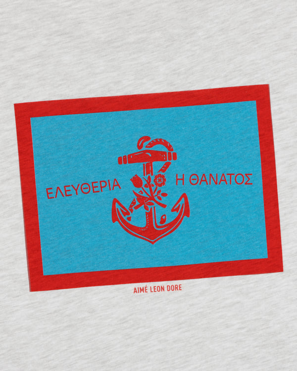 A blue and red anchor graphic with Greek text and Aimé Leon Dore on the light gray Coastal Flag Tee.
