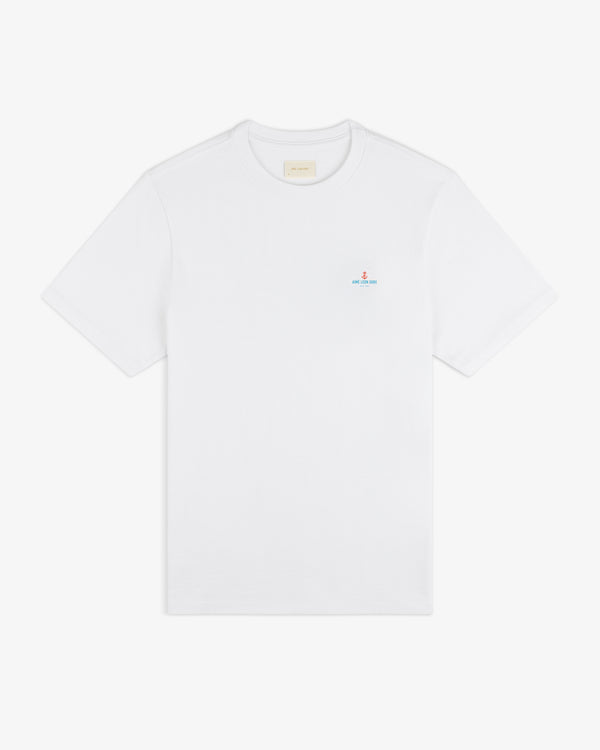 Coastal Flag Tee: plain white short-sleeve t-shirt with small blue and red text logo on left chest.