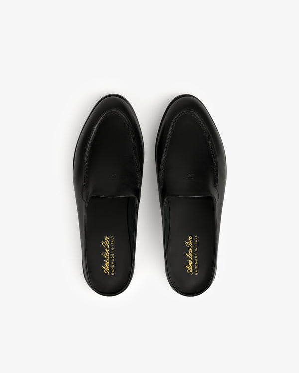 A pair of black Venetian Mule leather slip-on loafers with gold insole branding, viewed from above on white.