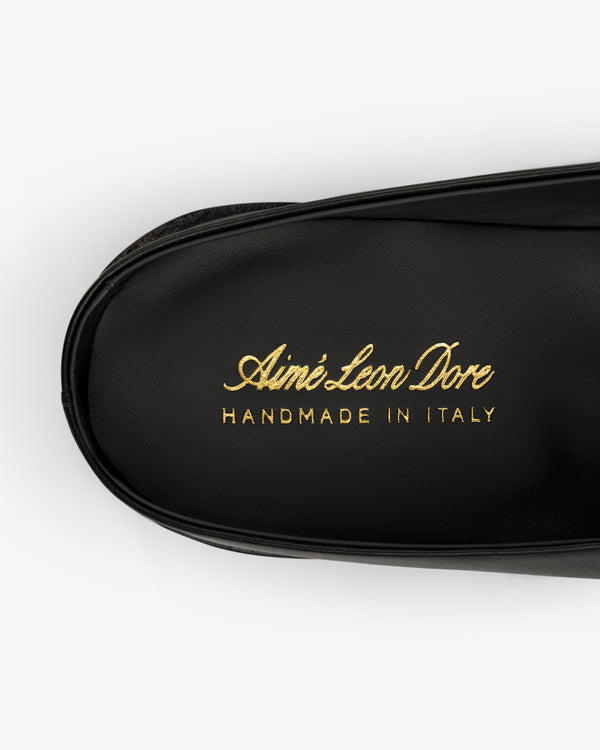 Close-up of a black leather Venetian Mule with gold text: Aimé Leon Dore HANDMADE IN ITALY.