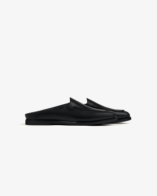 Venetian Mule: black leather slip-on mules with flat soles, pictured in profile on a white background.
