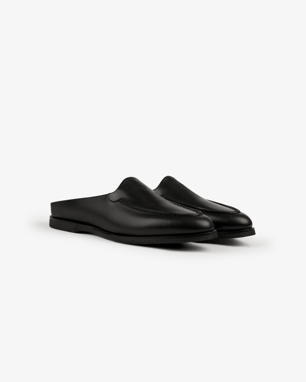 Venetian Mule: black leather slip-on shoes with low heel and minimalist design, shown on a white background.