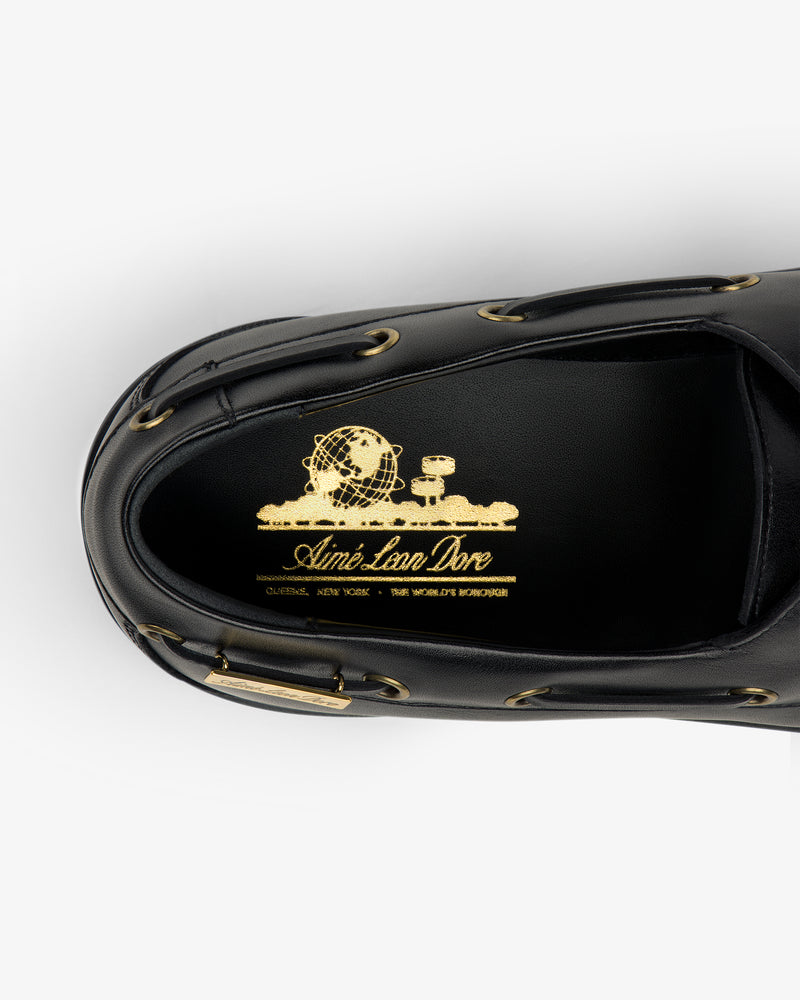 Top view of the Pápia Boat Shoe in black with gold Aimé Leon Dore branding and a globe graphic on the insole.