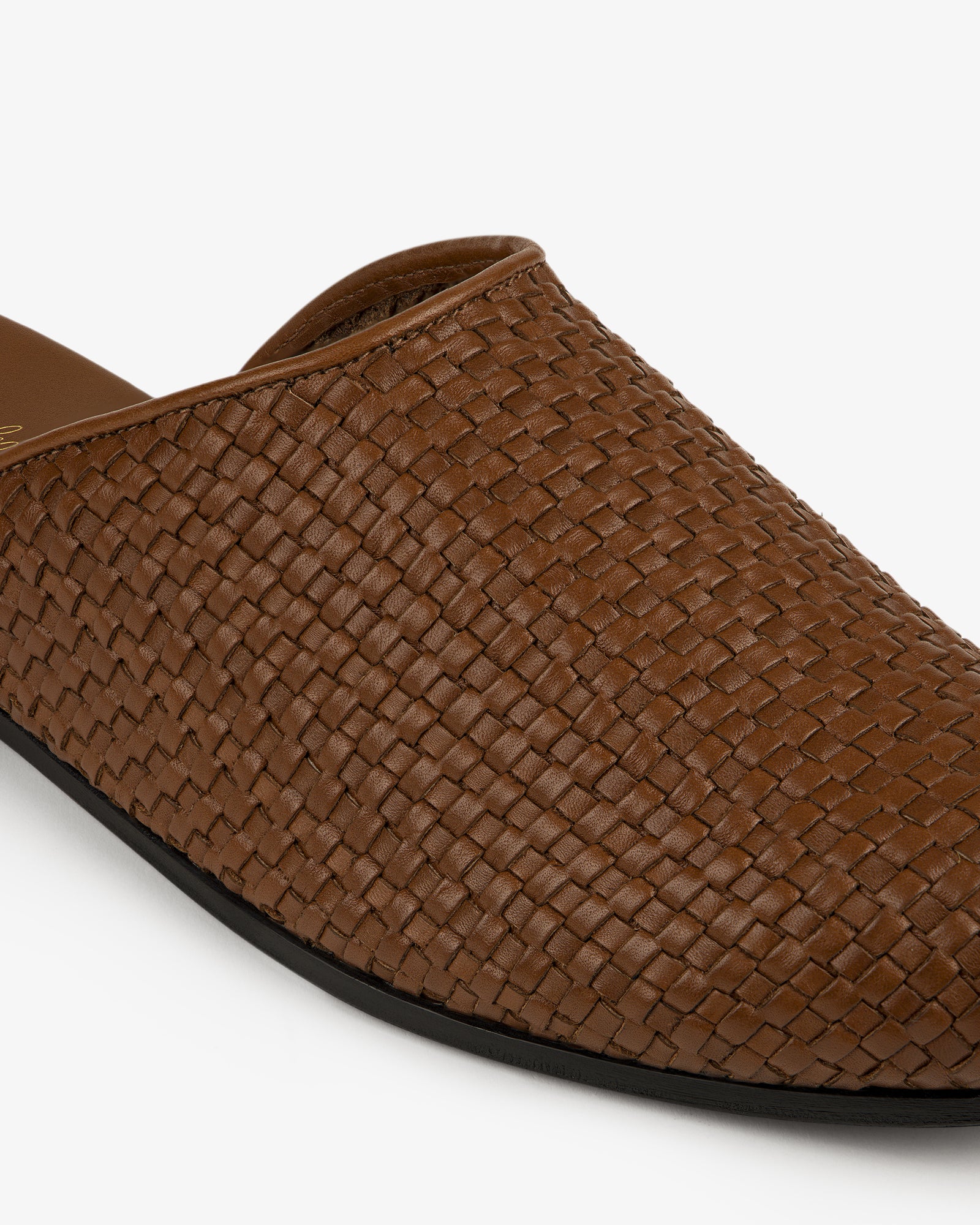 Close-up of a Leather Raffia Mule with brown woven leather and a black sole on a white background.