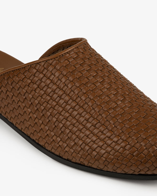 Close-up of a Leather Raffia Mule with brown woven leather and a black sole on a white background.