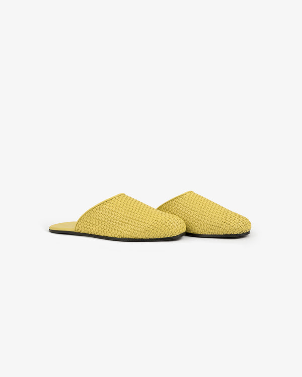 A pair of yellow Leather Raffia Mule slippers with closed toes and flat black soles on a white background.