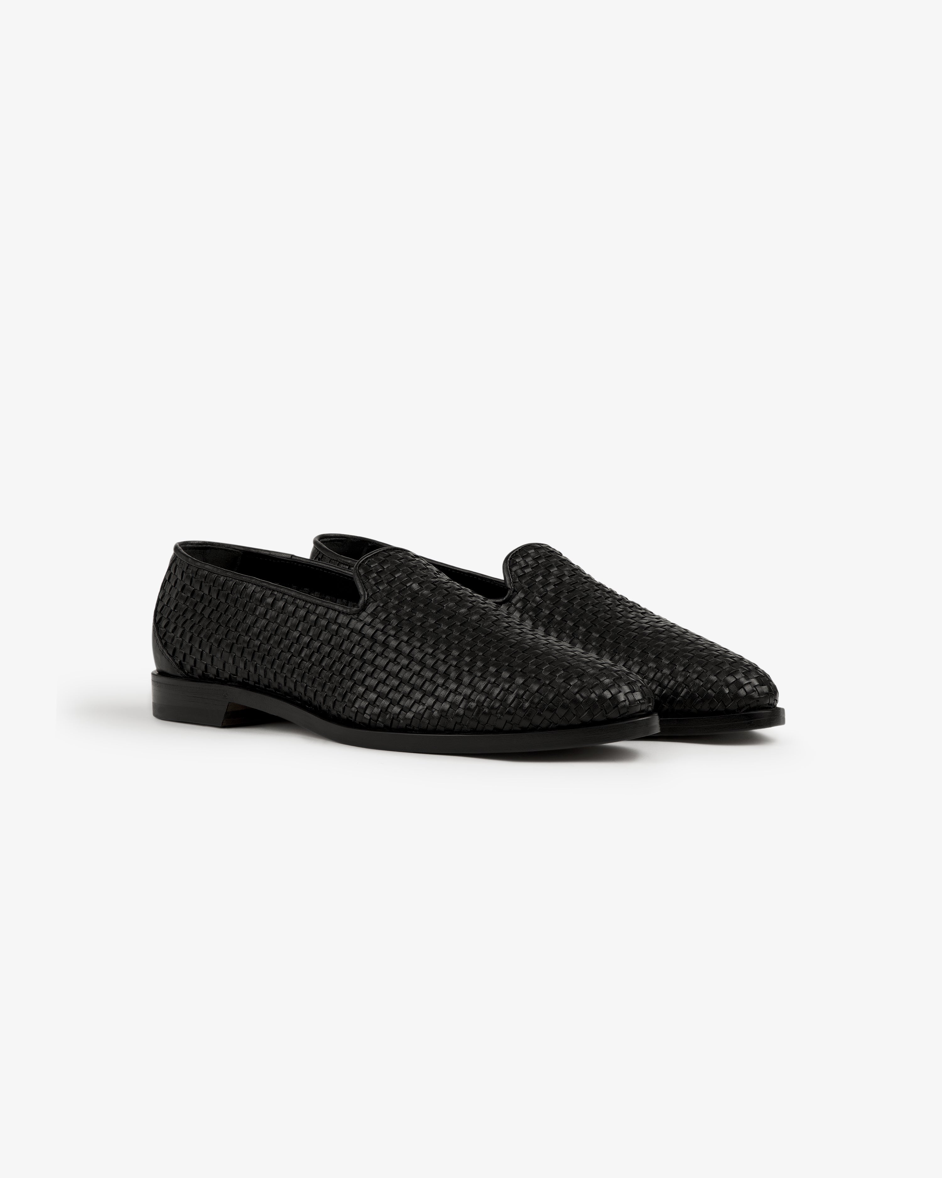A pair of Leather Raffia Loafers in black woven leather with low heels displayed on a white background.