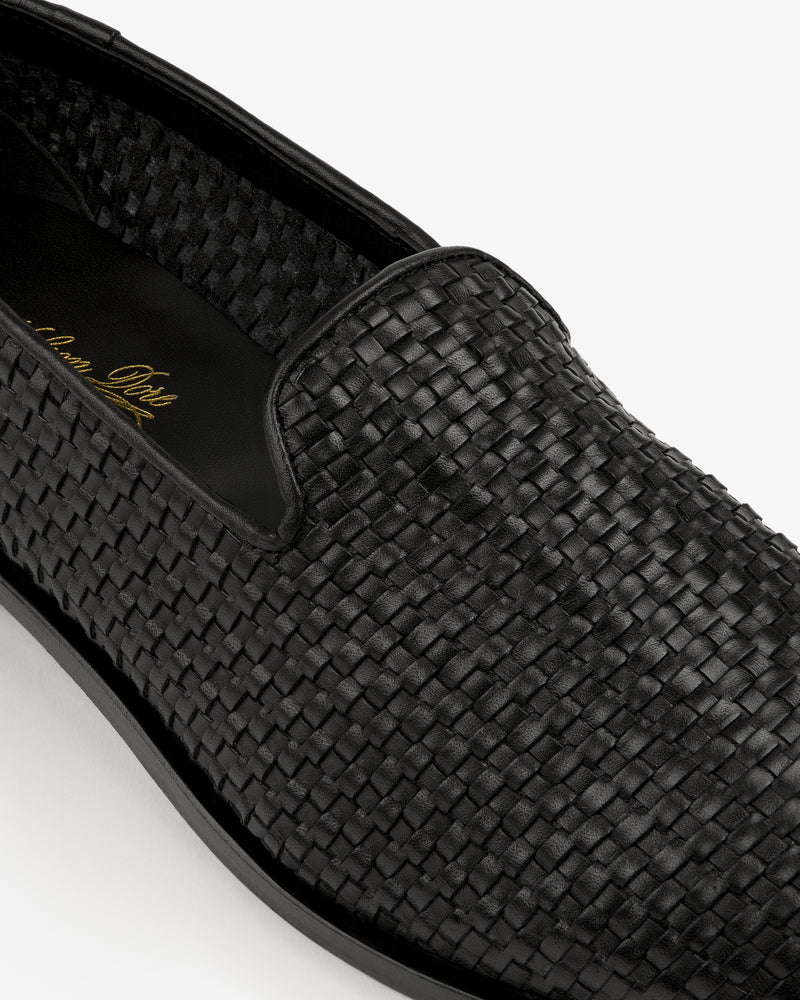 Close-up of the Leather Raffia Loafer, a black woven leather slip-on with rounded toe and black sole.
