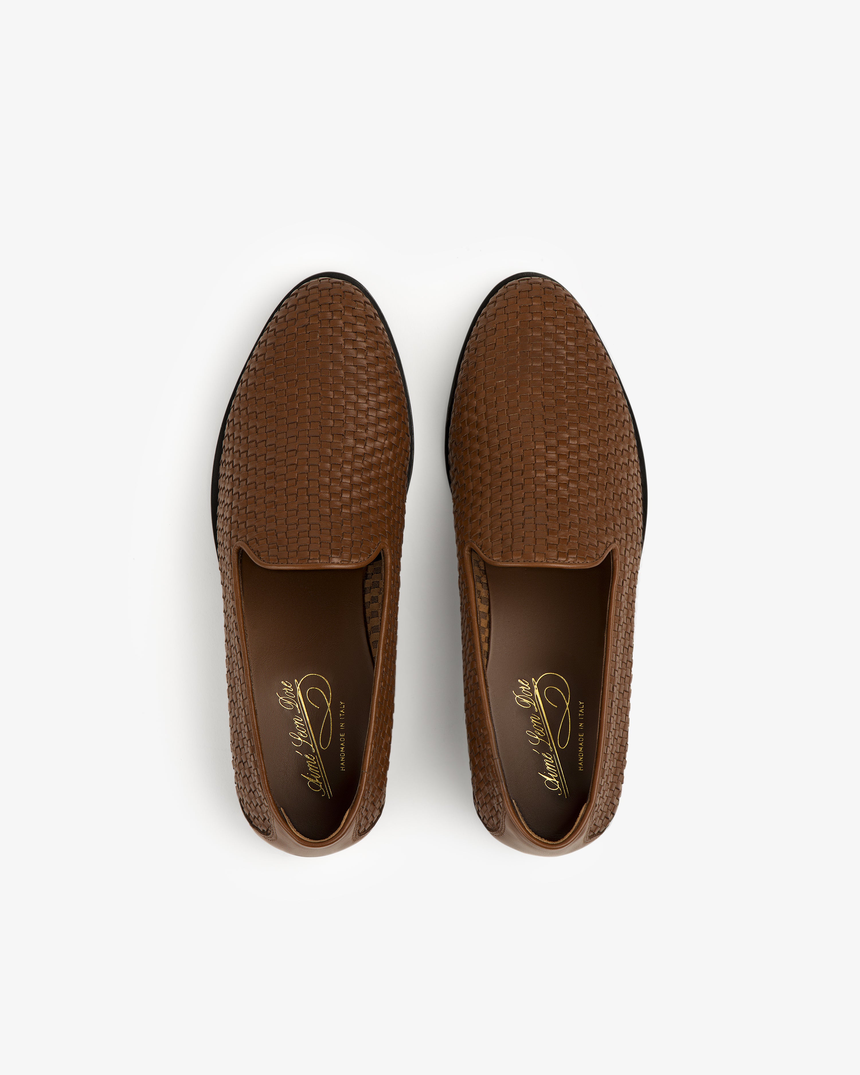 The Leather Raffia Loafer: brown, textured slip-ons with a woven pattern, shown from above on a white background.