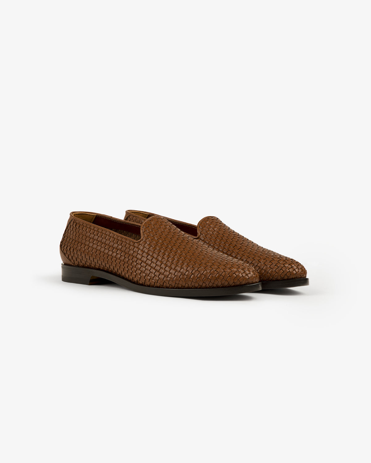 The Leather Raffia Loafer: brown woven leather, low heels, shown on a white background.