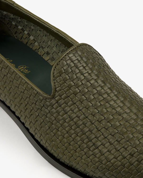 Close-up of a Leather Raffia Loafer in green woven leather with a black sole on a white background.