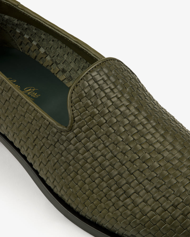 Close-up of a Leather Raffia Loafer in green woven leather with a black sole on a white background.