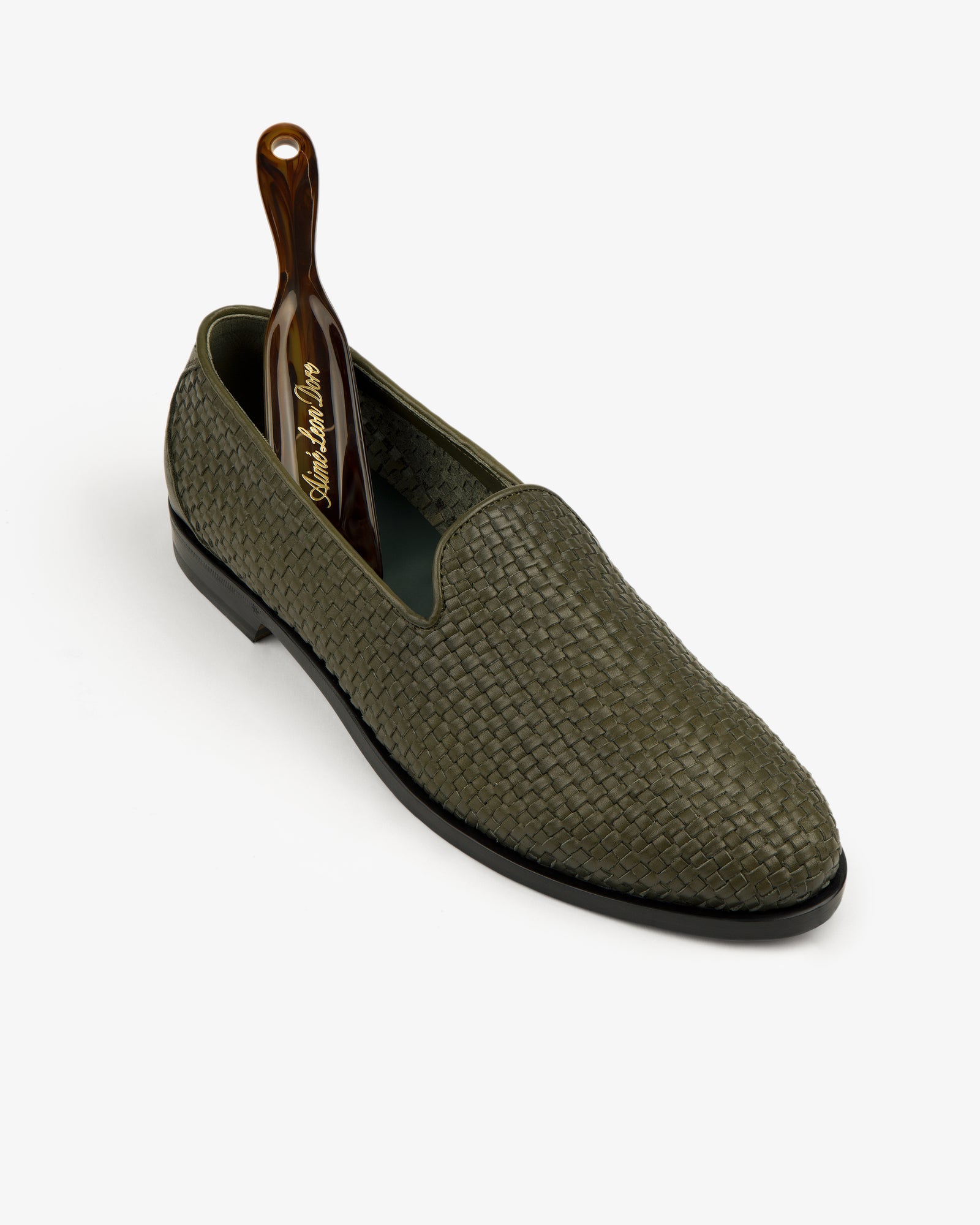 A green Leather Raffia Loafer with a brown shoehorn inside, shown against a white background.