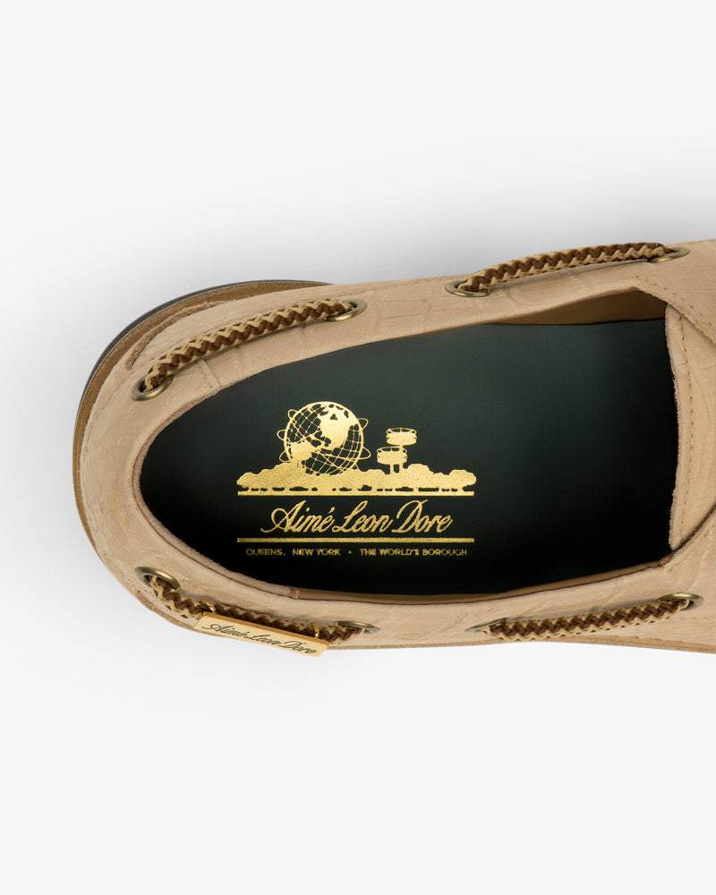 Top view of a tan Pápia Boat Shoe with a gold Aimé Leon Dore logo on the black insole.