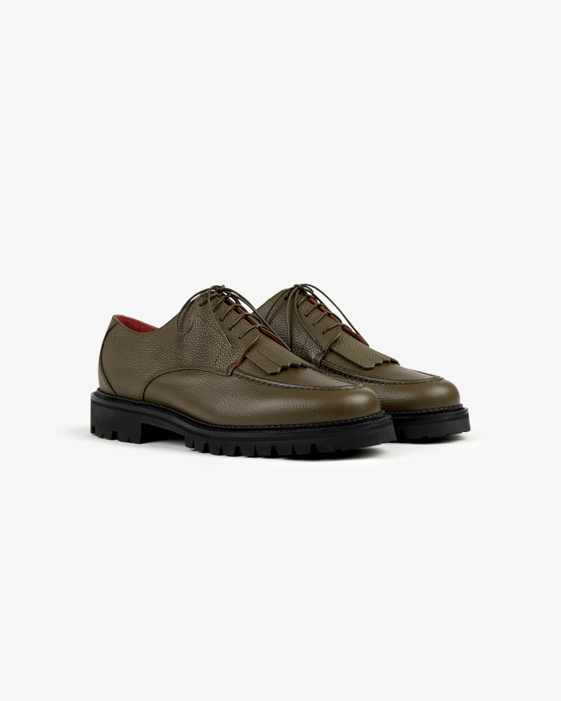 Leather Lug Sole Derby in olive green leather with black chunky soles and brown laces, on a white background.