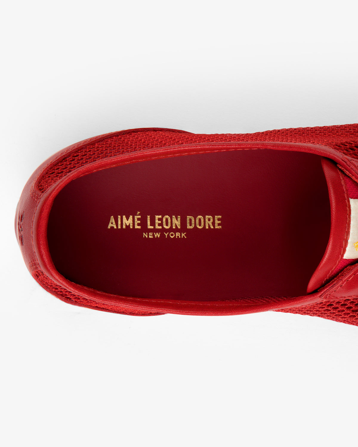 Top view of the Low Profile Mesh Trainer in red with AIMÉ LEON DORE NEW YORK gold lettering on the insole.