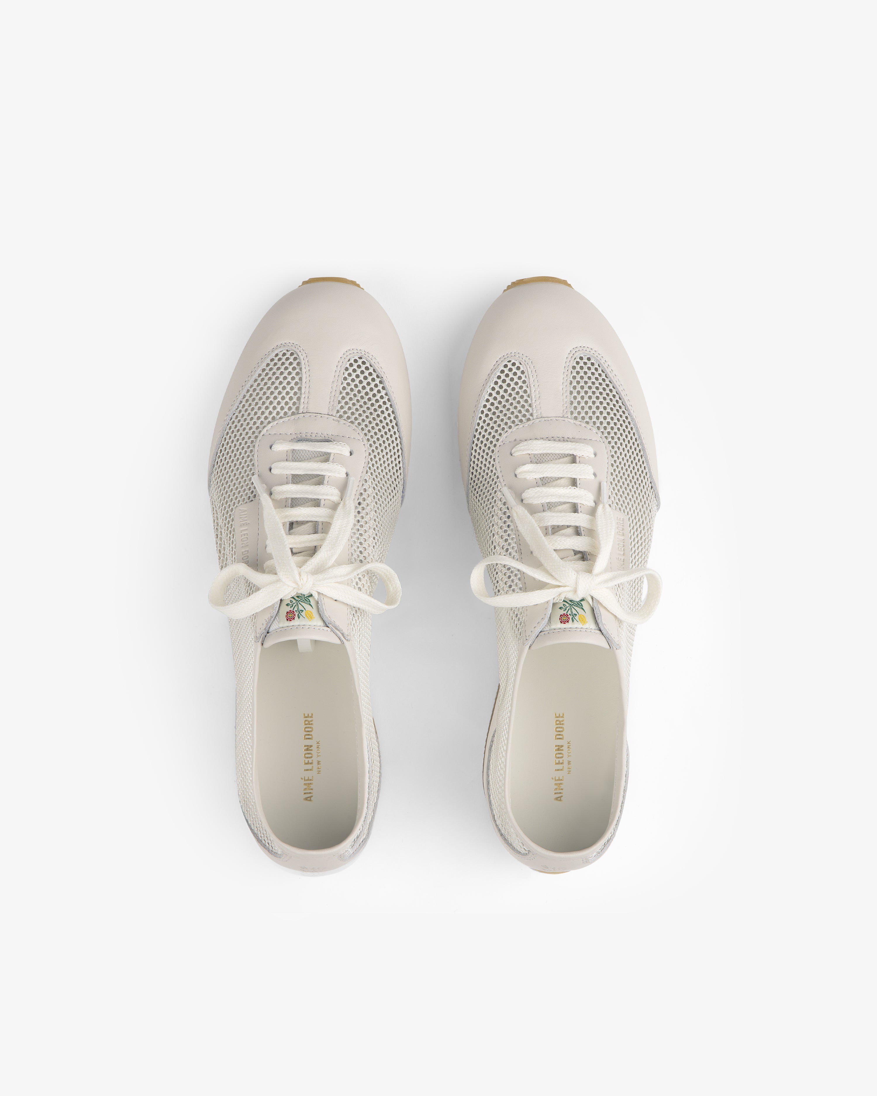Top view of Low Profile Mesh Trainer sneakers in white mesh and leather with laces on a plain white background.