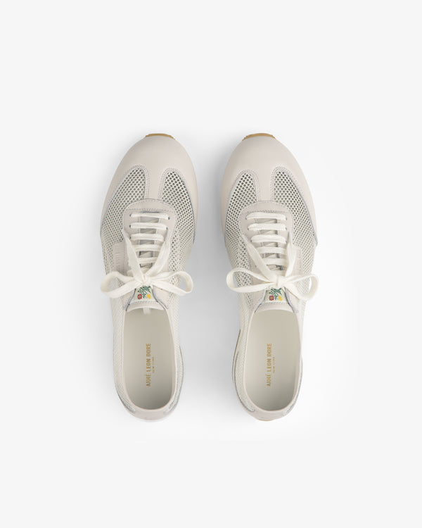 Top view of Low Profile Mesh Trainer sneakers in white mesh and leather with laces on a plain white background.