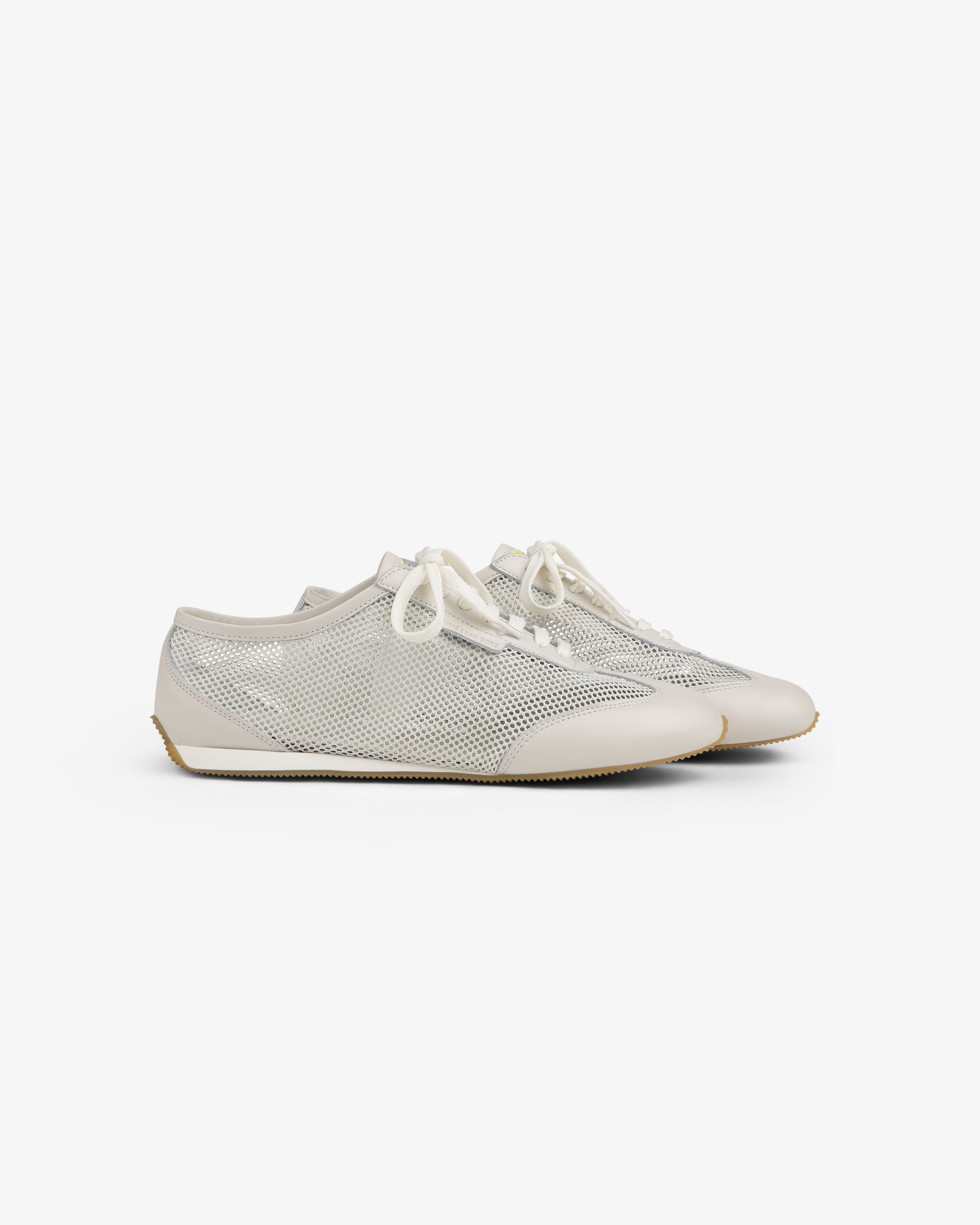 Low Profile Mesh Trainer: White mesh sneakers with cream soles and laces, displayed on a plain background.