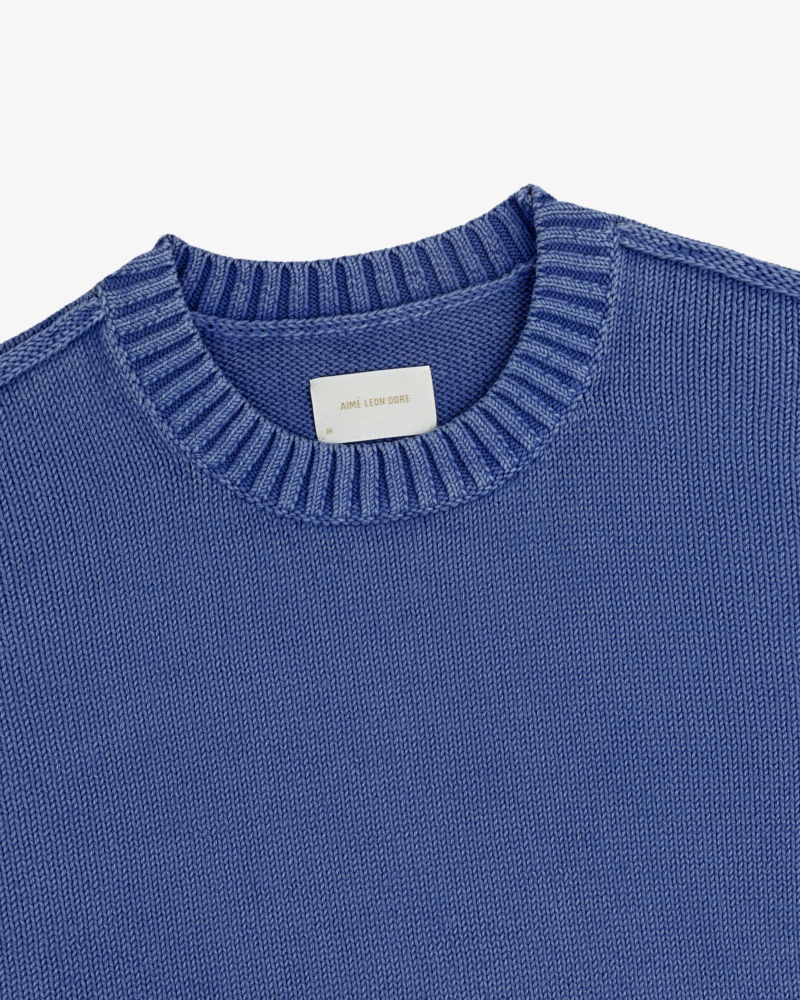 Washed Inside Out Sweater in blue with ribbed crewneck and visible white collar tag, on a white background.