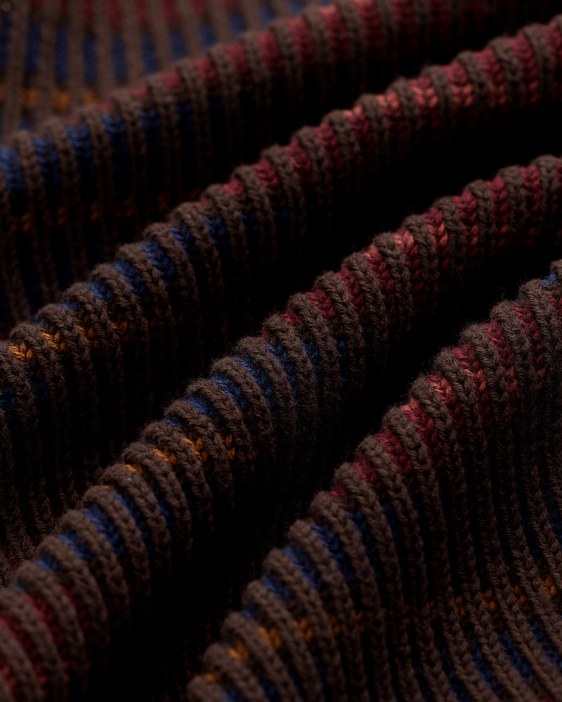 Close-up of the Multi Color Knit Track Sweater showing ribbed fabric with dark brown, blue, and red wavy stripes.