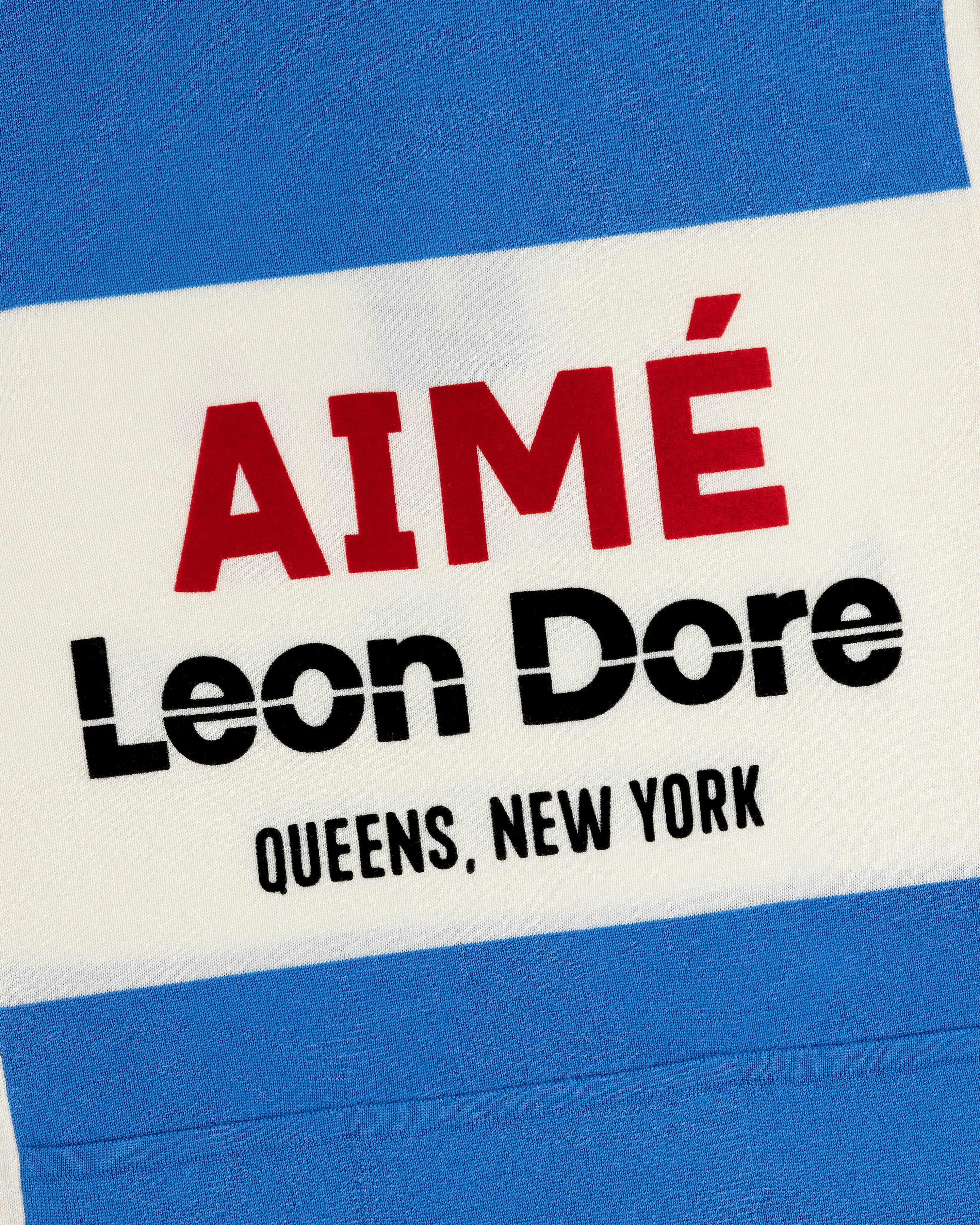 Close-up of a Merino Wool Cycling Jersey with AIMÉ Leon Dore QUEENS, NEW YORK on blue and white stripes.