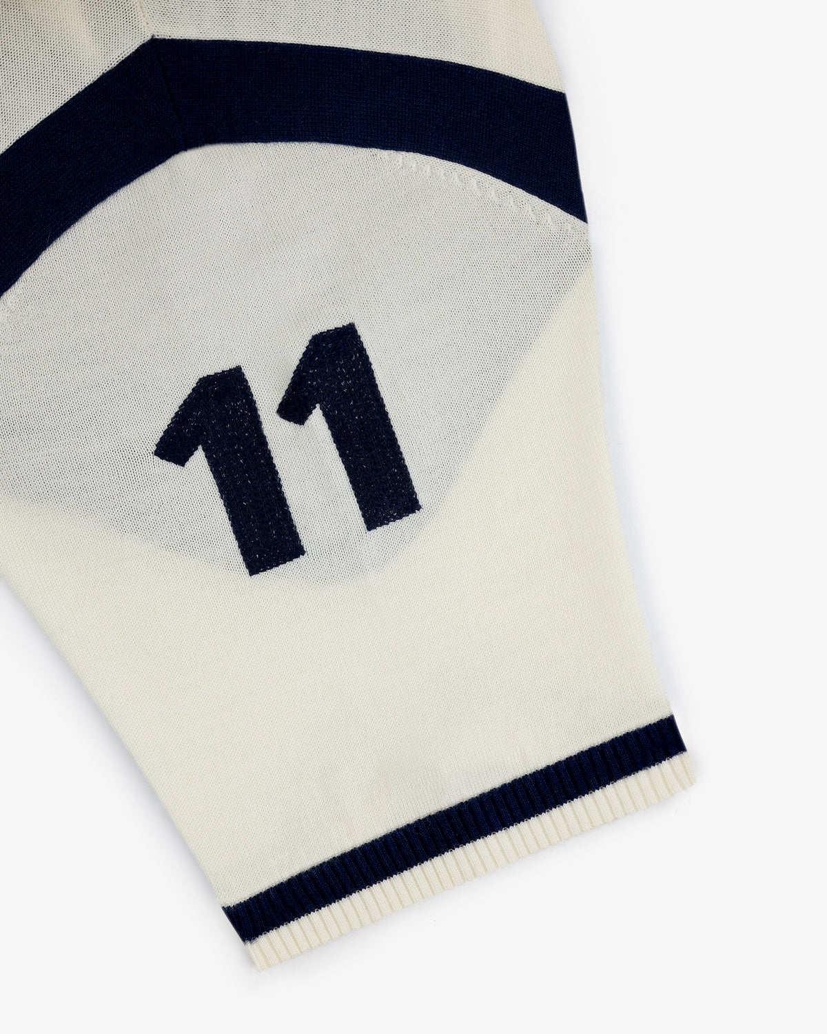 Close-up of a Merino Wool Cycling Jersey’s cream sleeve with navy blue number 11 and stripes near the edge.