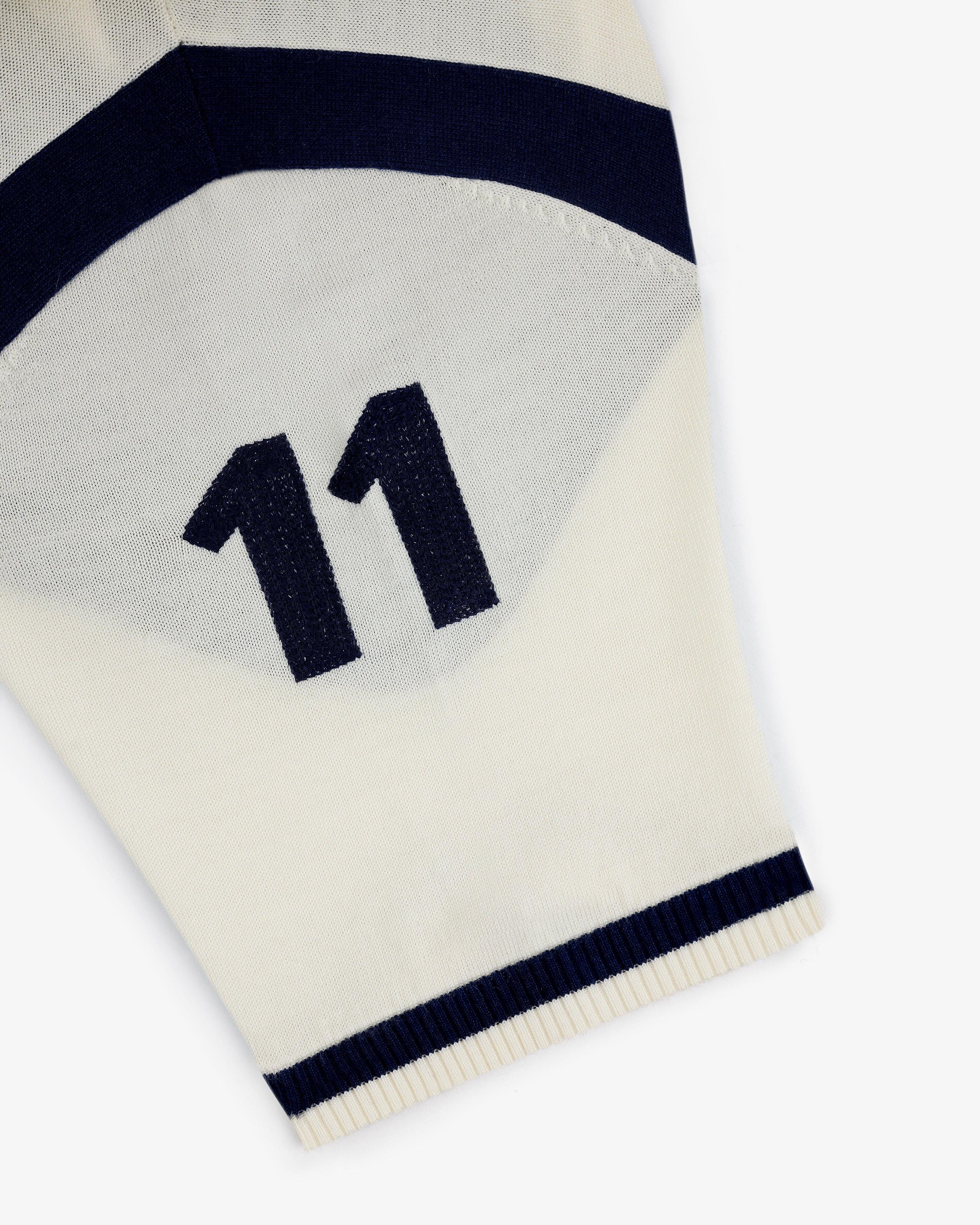 Close-up of a Merino Wool Cycling Jersey’s cream sleeve with navy blue number 11 and stripes near the edge.