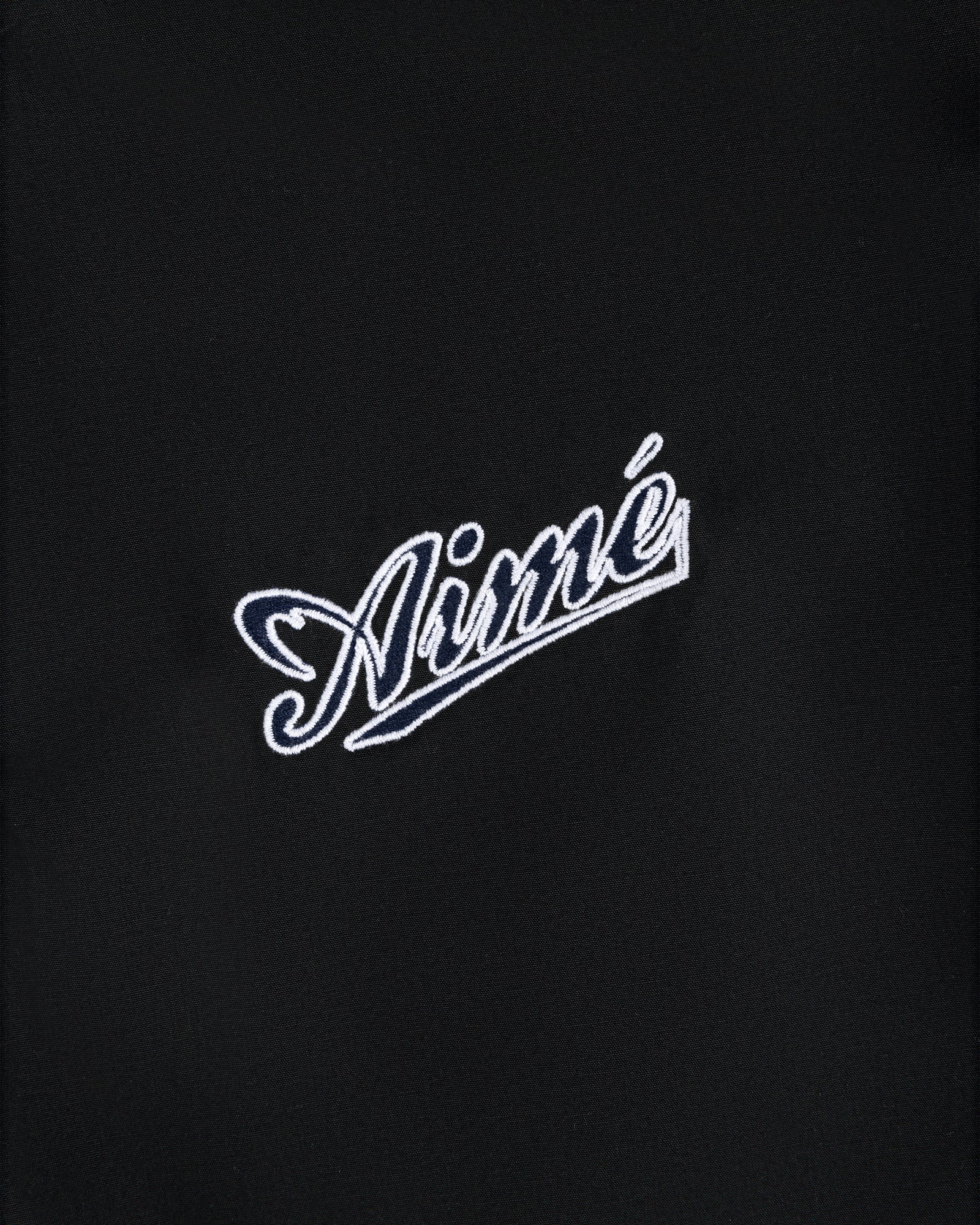 White script text Aimé embroidered on a plain black Reversible Knit Bomber Jacket.