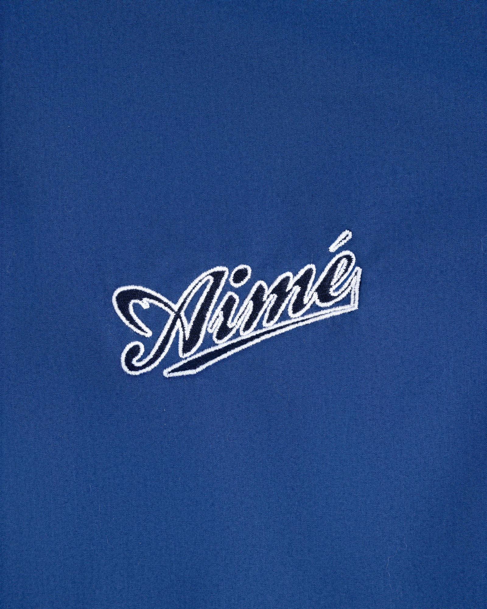 Blue Reversible Knit Bomber Jacket with "Aimé" embroidered in white cursive at the center.