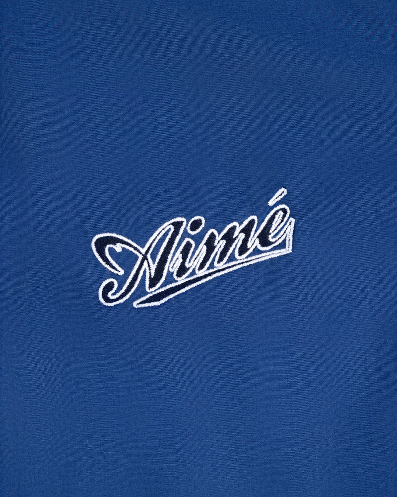 Blue Reversible Knit Bomber Jacket with "Aimé" embroidered in white cursive at the center.