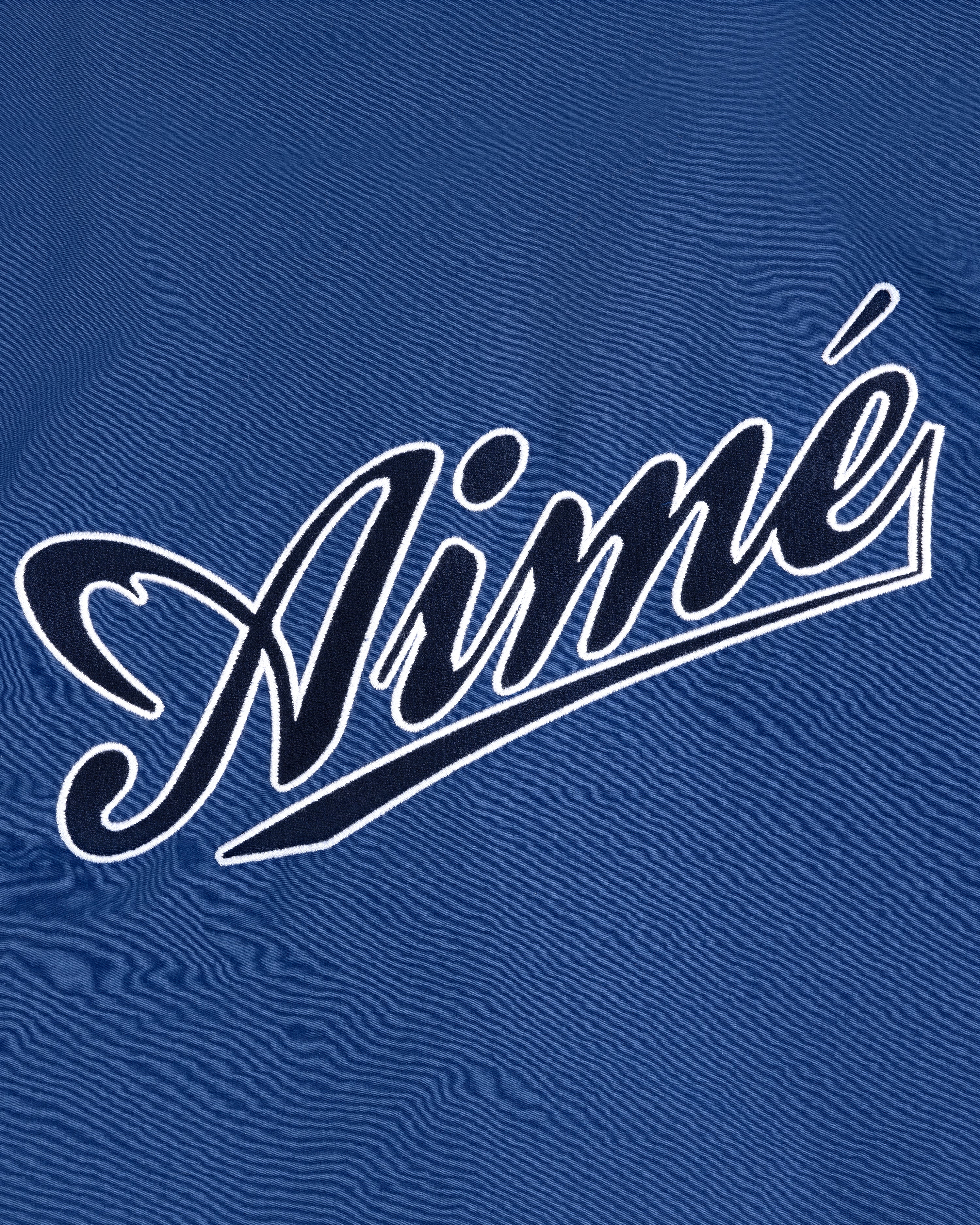 Blue fabric Reversible Knit Bomber Jacket with "Aimé" in large, white, cursive outlined letters across the front.