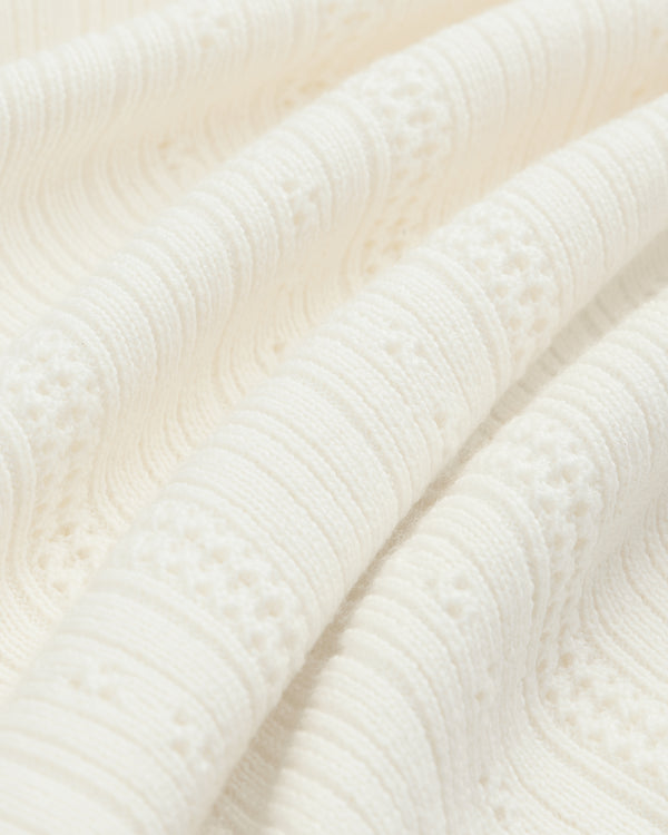 Close-up of the Merino Wool Eyelet Tee’s textured off-white fabric with raised ridges and woven patterns.