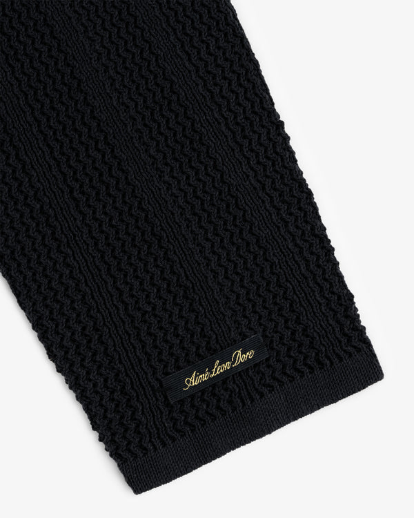Close-up of the black Racking Stitch Crewneck Sweater with a small black and gold Aimé Leon Dore label.