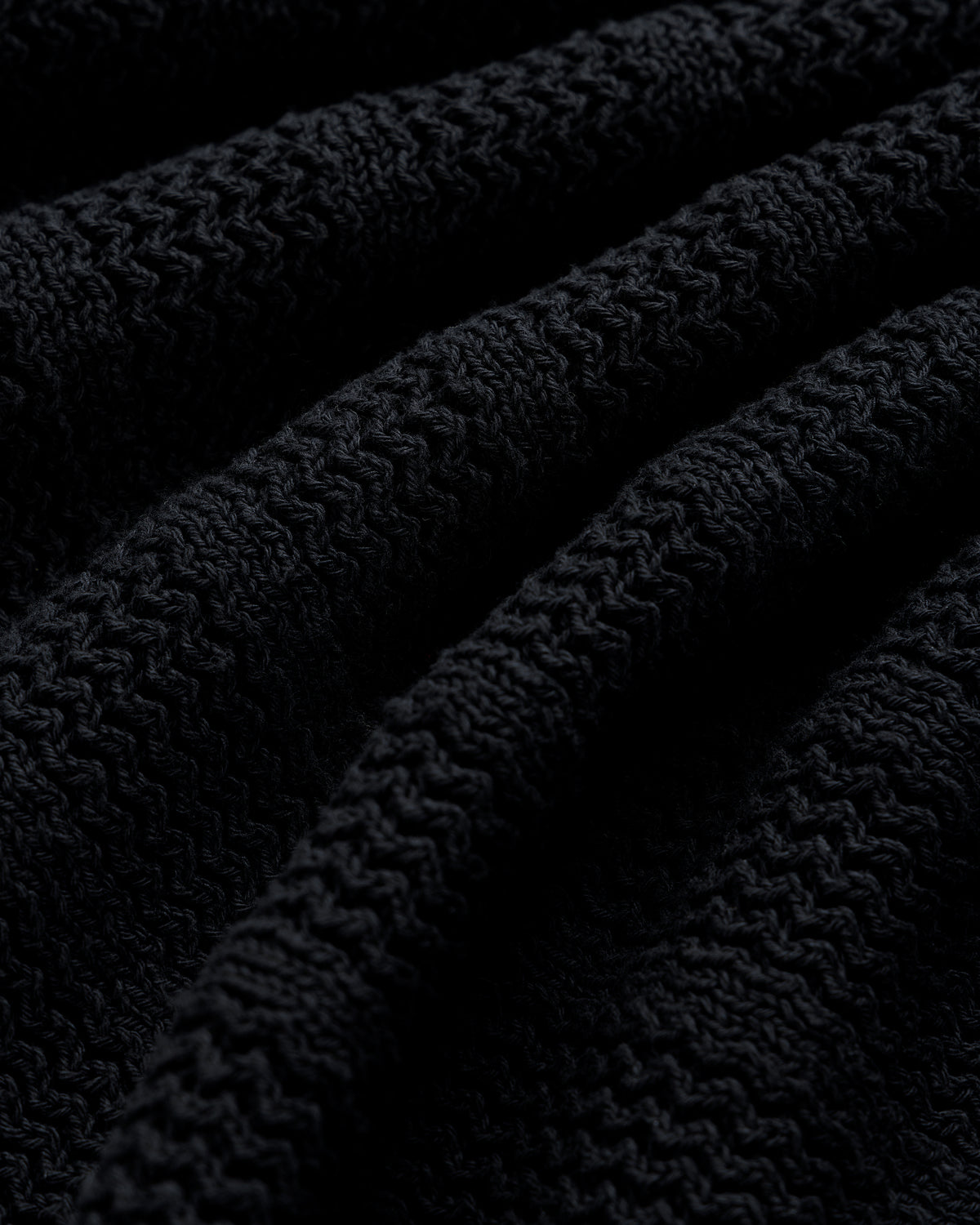 Close-up of the Racking Stitch Crewneck Sweater’s textured black knit with visible ridges and wavy patterns.