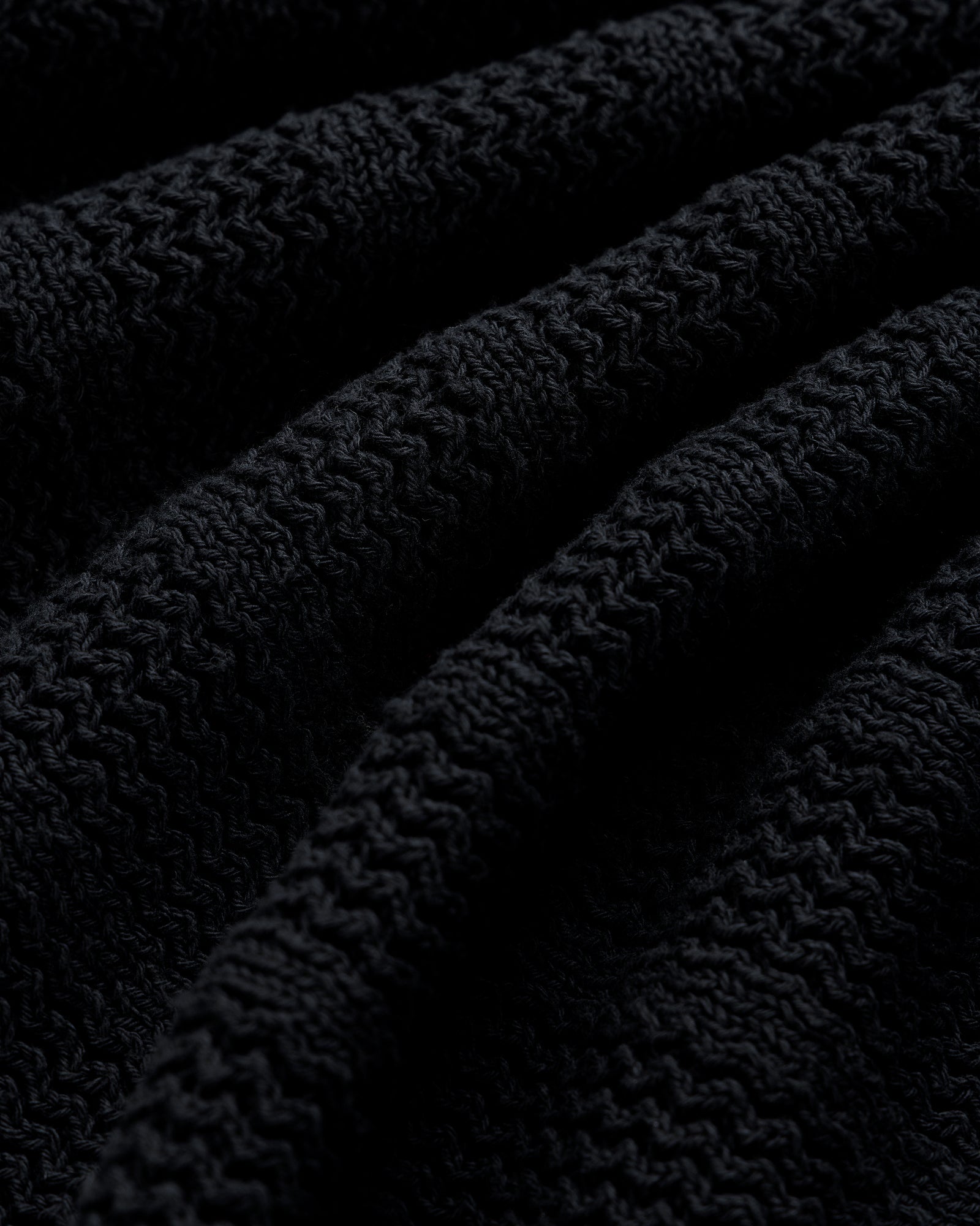 Close-up of the Racking Stitch Crewneck Sweater’s textured black knit with visible ridges and wavy patterns.