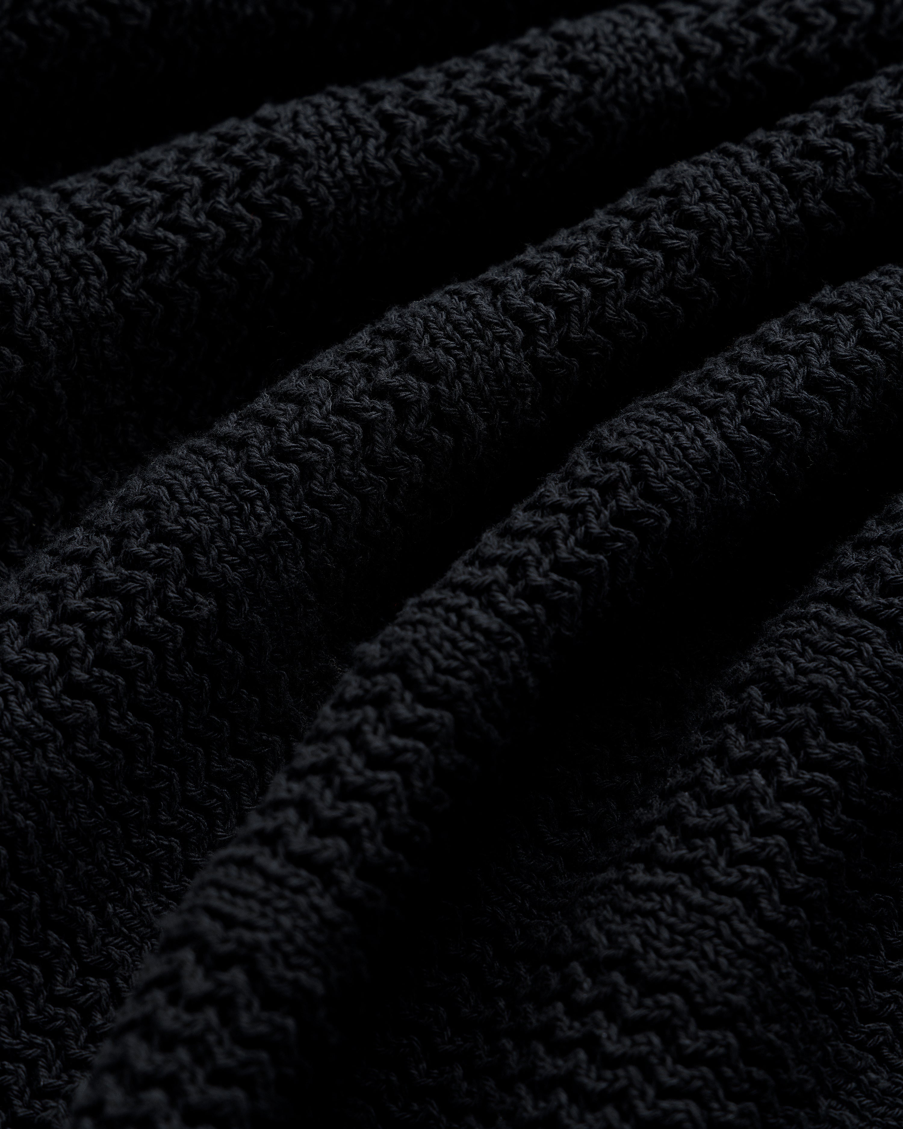 Close-up of the Racking Stitch Crewneck Sweater’s textured black knit with visible ridges and wavy patterns.