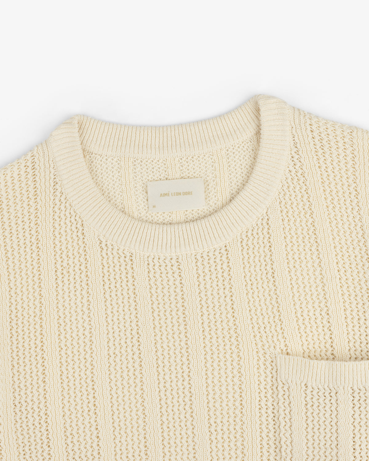 The Racking Stitch Crewneck Sweater is beige with a textured knit, round neckline, and chest pocket on a white background.