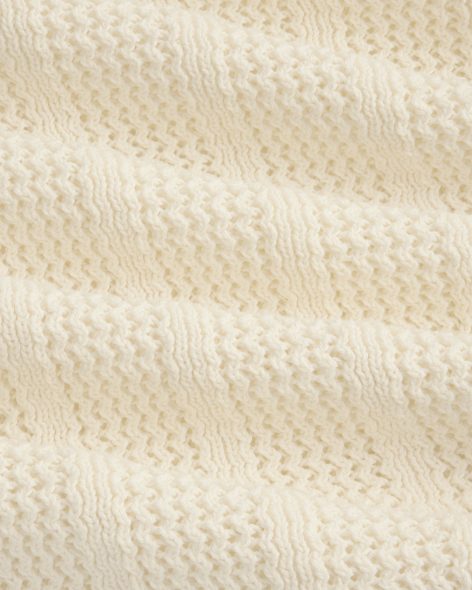 Close-up of the Racking Stitch Crewneck Sweater's soft, cream knit with a textured, wavy pattern.