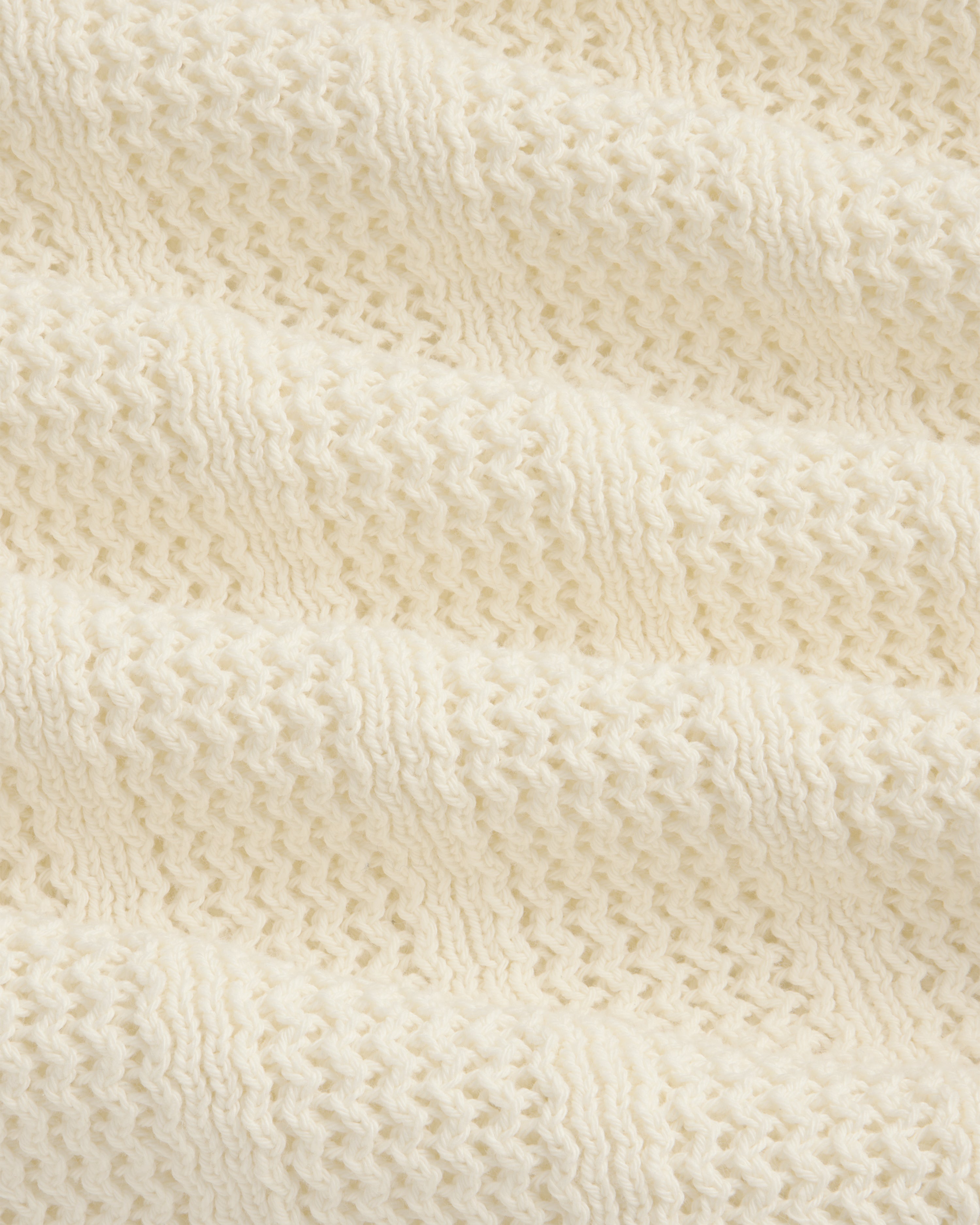 Close-up of the Racking Stitch Crewneck Sweater's soft, cream knit with a textured, wavy pattern.