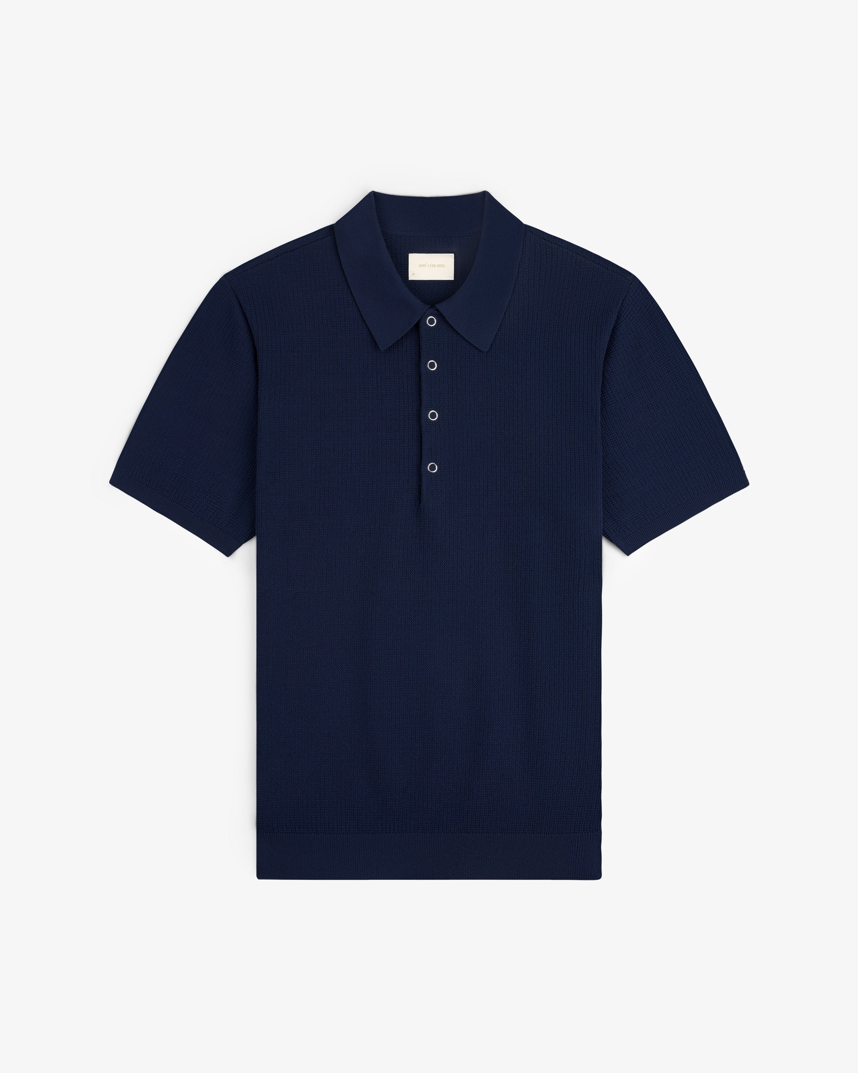 Navy Knit Polo with short sleeves, classic collar, and three buttons, laid flat on a white background.