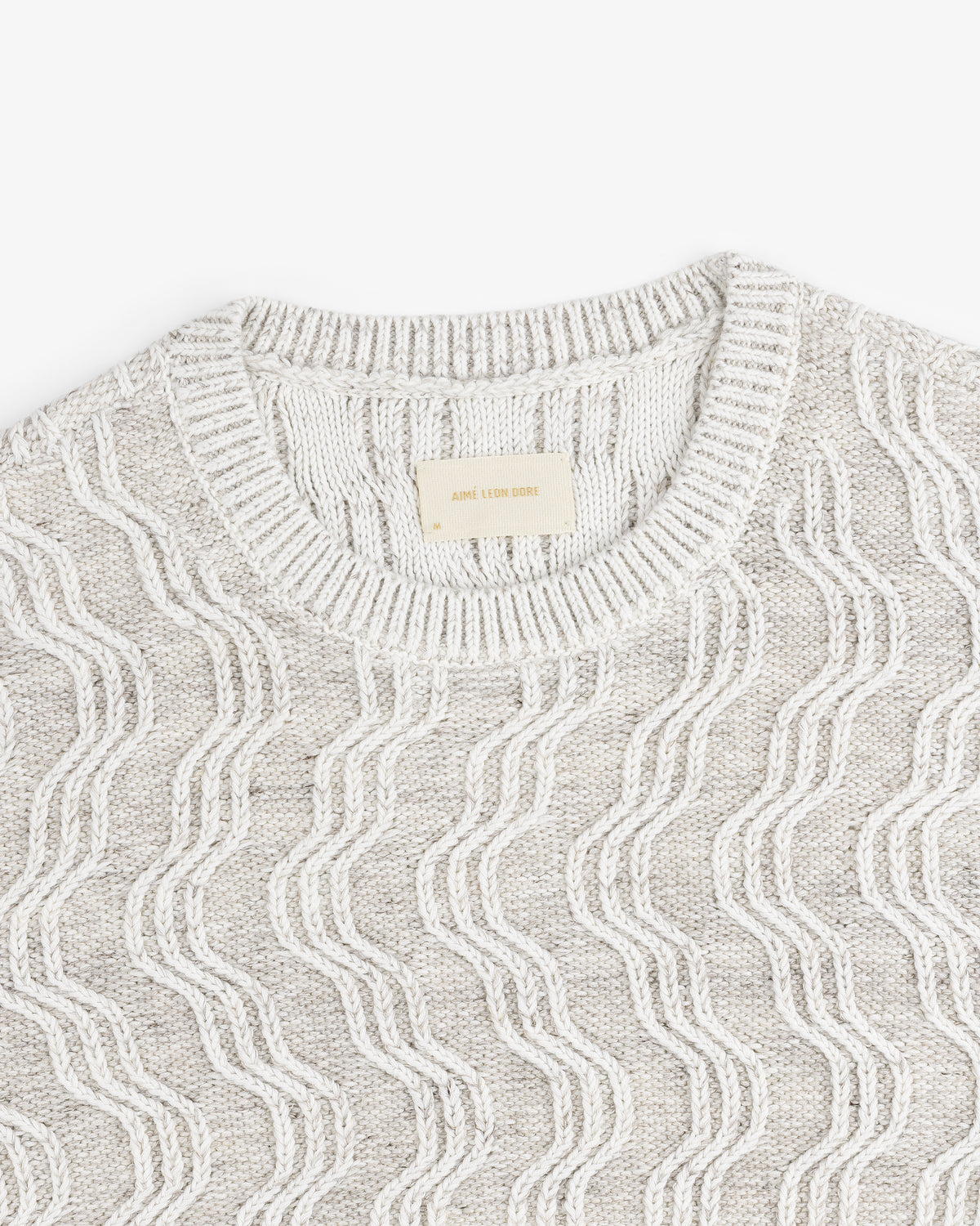Linen Blend Cable Knit Sweater in light gray with a wavy white pattern and ribbed crew neckline, shown from above.