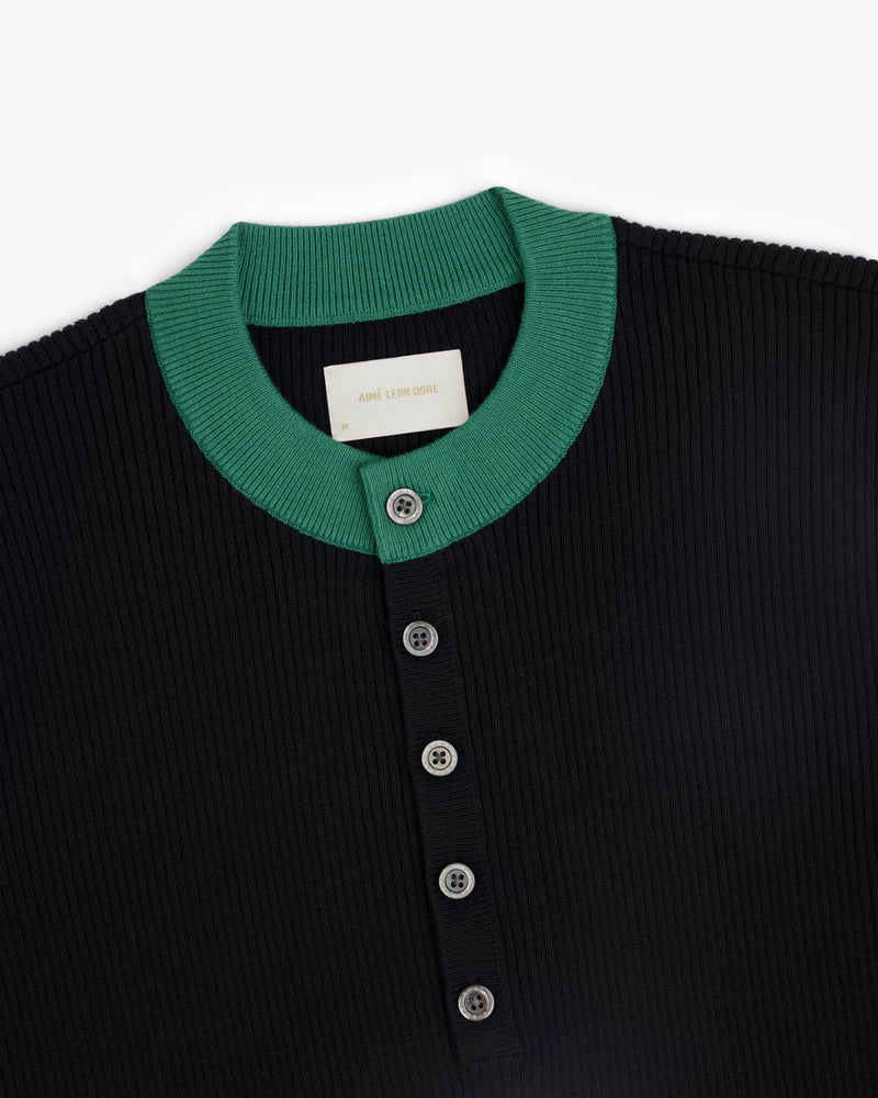 Close-up of the Sport Knit Henley, a ribbed black shirt with a green collar and four front buttons.
