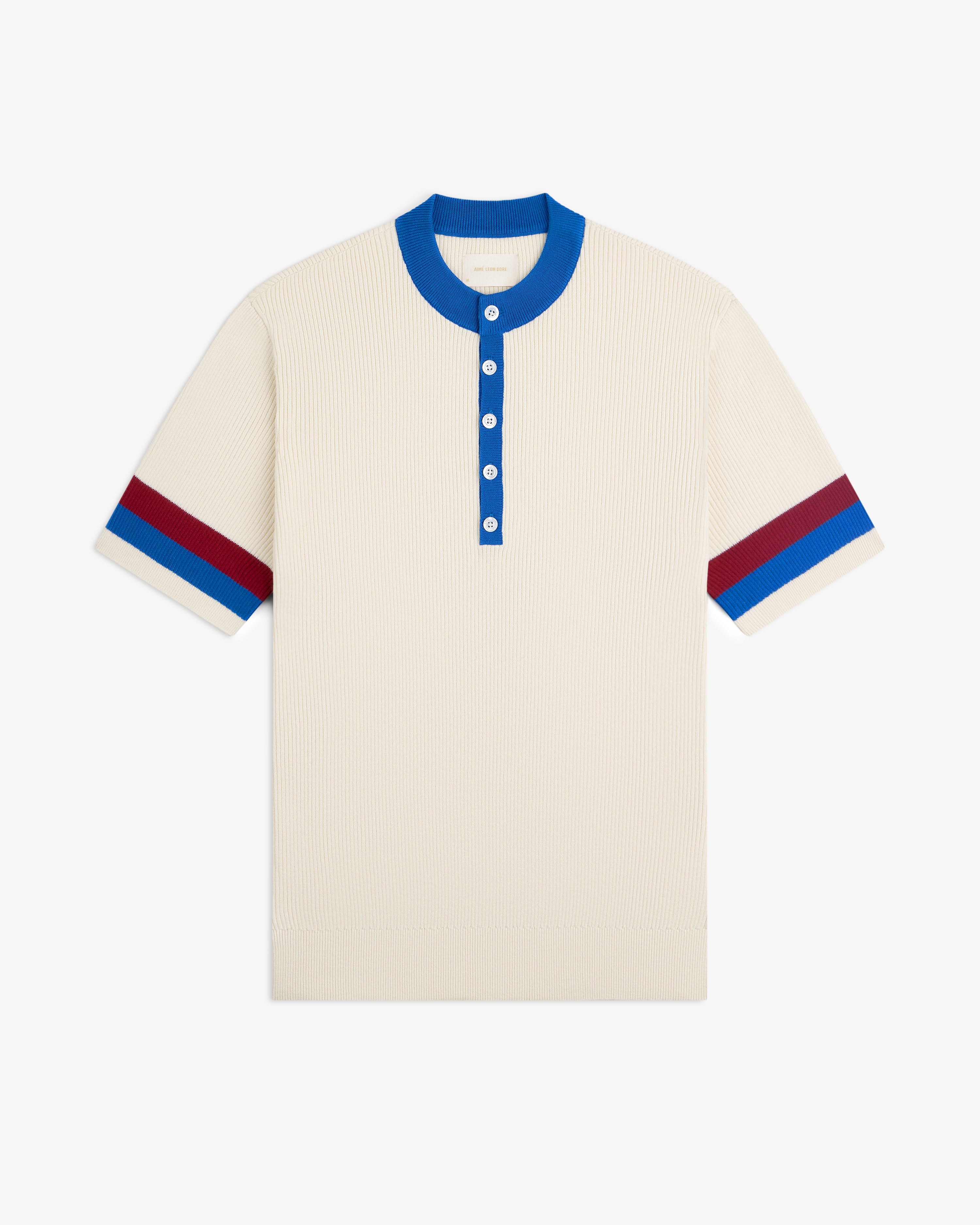 Sport Knit Henley: Cream short-sleeve knit shirt with blue collar, blue buttons, and red/blue sleeve stripes.