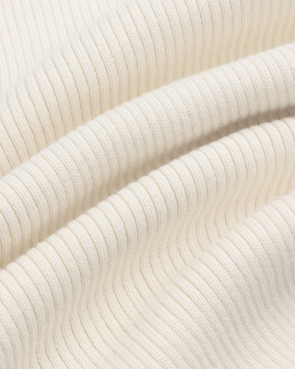 Close-up of Sport Knit Henley’s ribbed cream fabric, highlighting its soft texture and gentle folds.