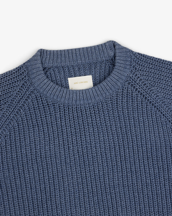 Knit Denim Crewneck Sweater with ribbed texture and visible neck label, laid flat on a white background.