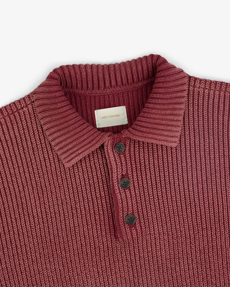 The Stone Washed Knit Polo is ribbed, maroon, with a collar and three black buttons down the front.