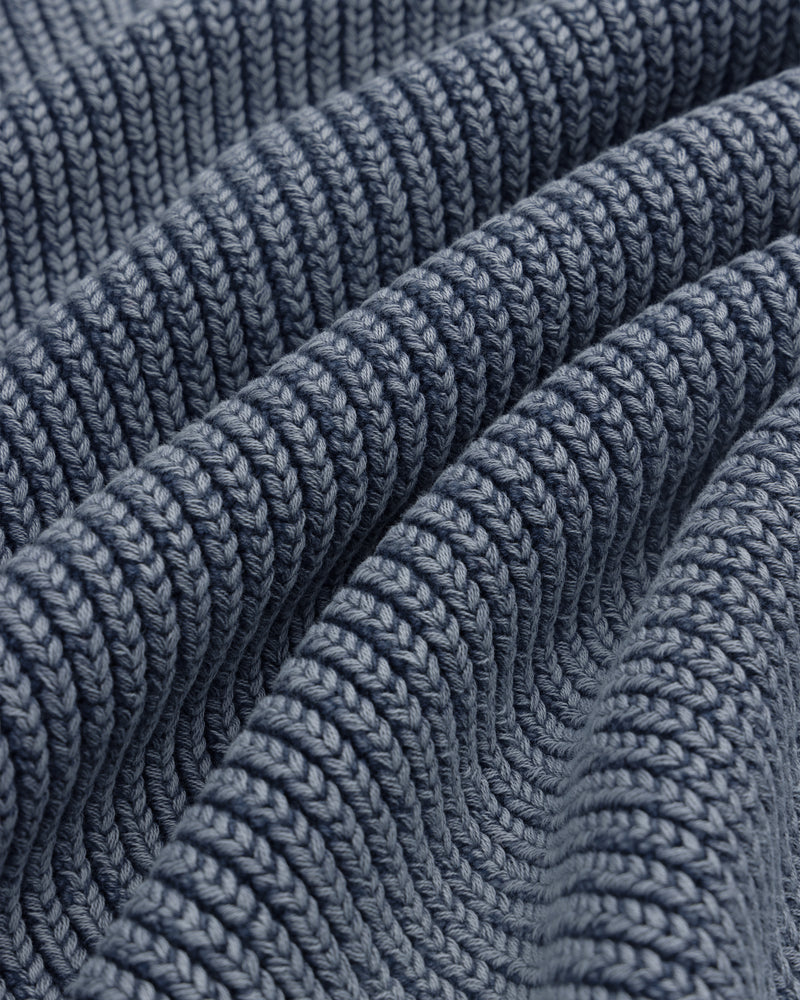 Close-up of thick, textured rows and soft folds on blue Stone Washed Knit Polo fabric.