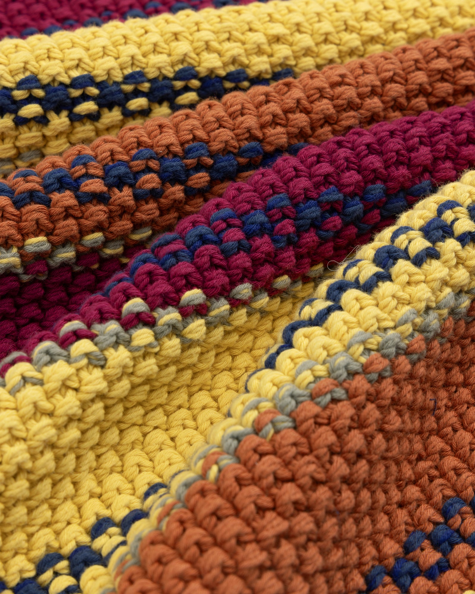 Close-up of a colorful Striped Rollneck Sweater with yellow, orange, burgundy, and blue yarn stripes.