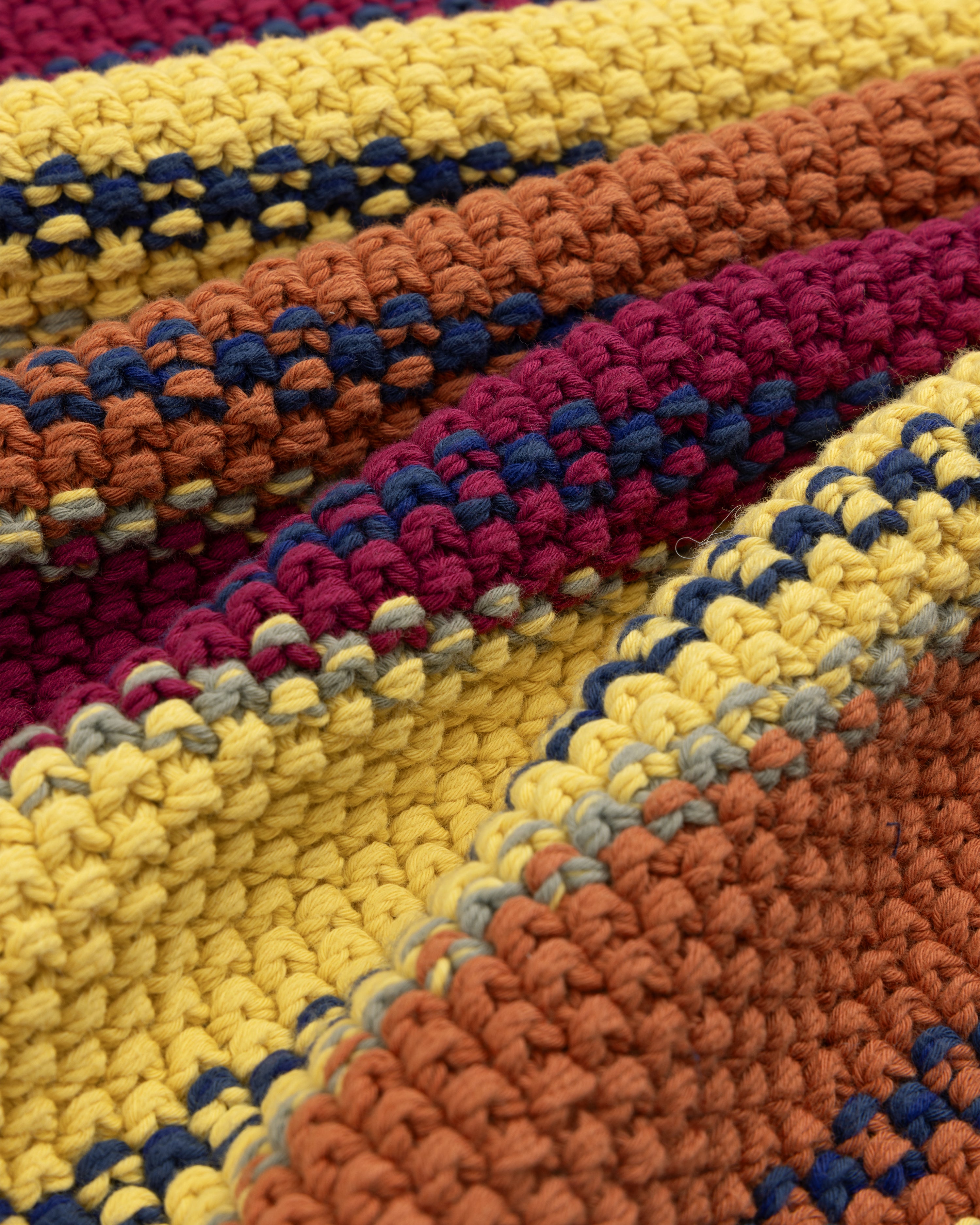 Close-up of a colorful Striped Rollneck Sweater with yellow, orange, burgundy, and blue yarn stripes.
